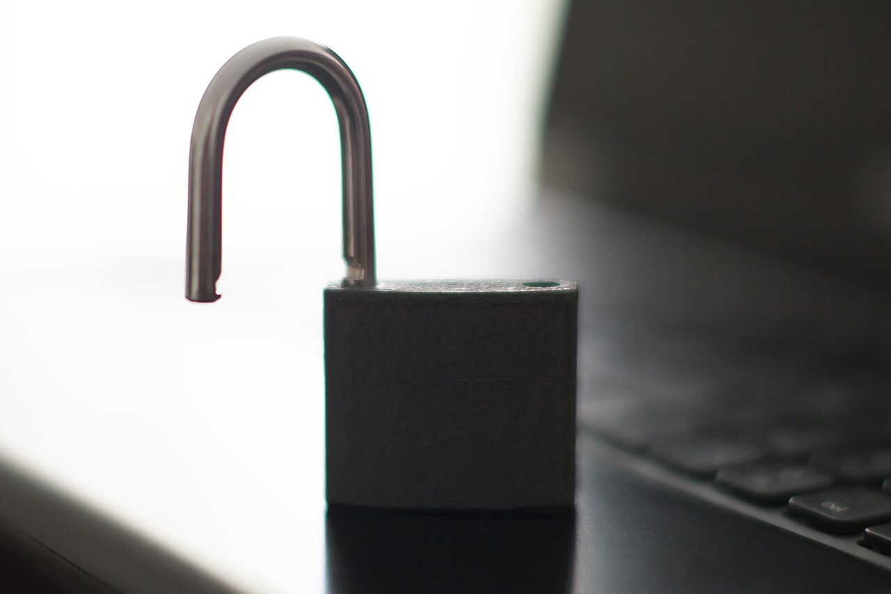 A silver padlock resting on the keyboard of an open laptop.