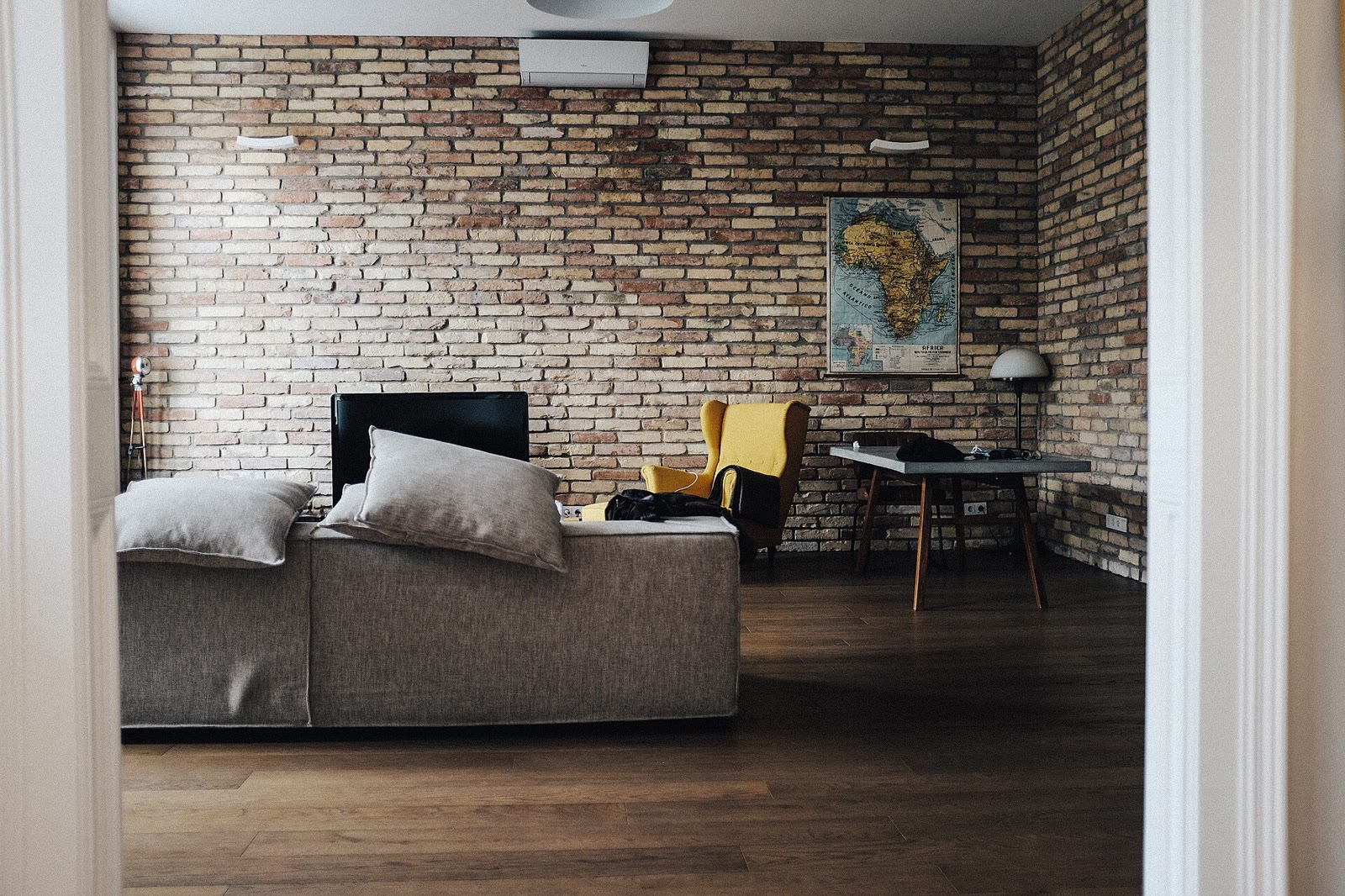 A bright living room with a wall-mounted television above a wooden cabinet, a sofa, and a coffee table.