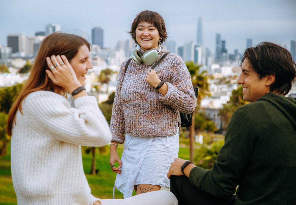 Three people outdoors wearing black Bee Pioneer devices on their wrists.