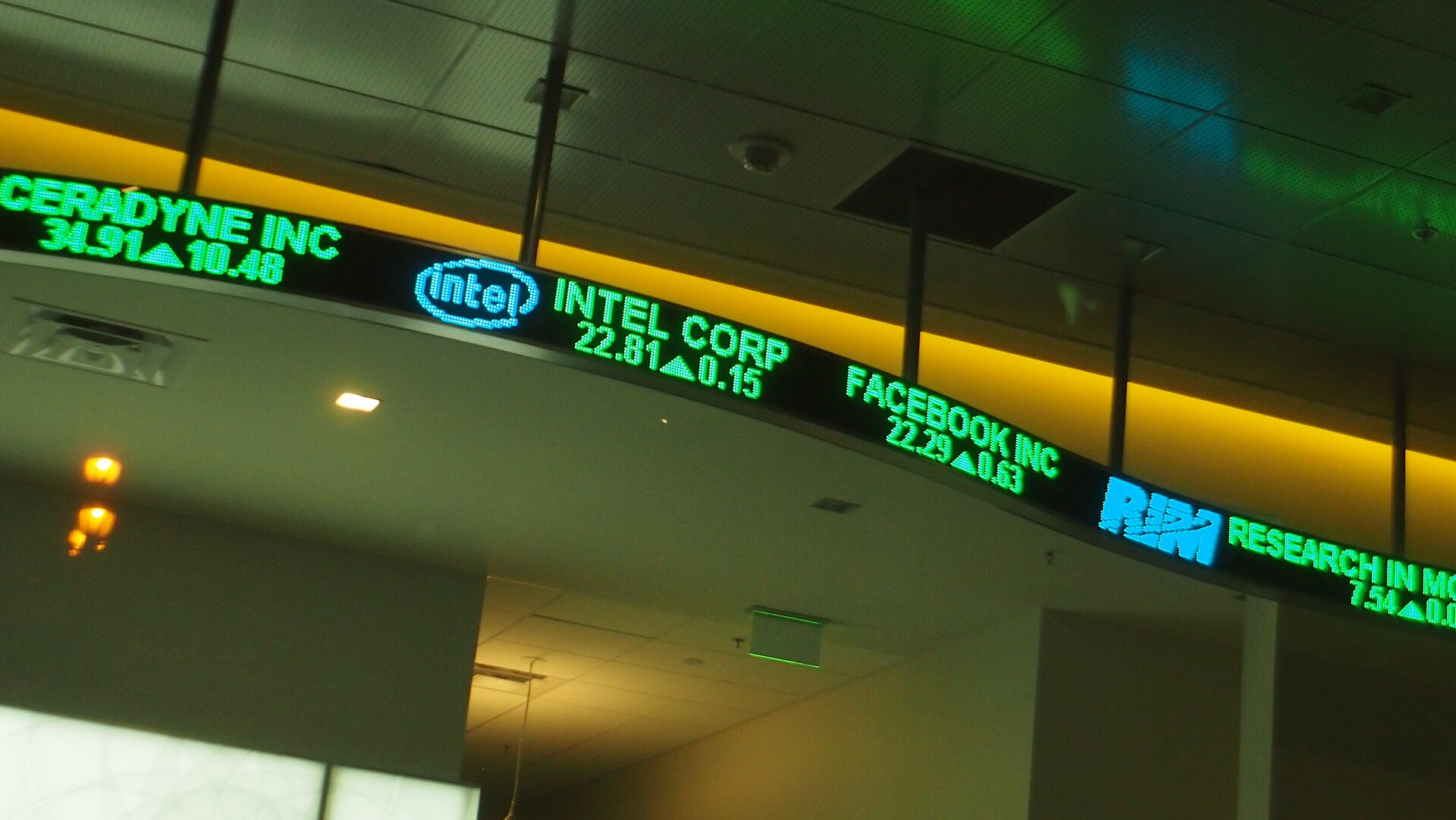 A close-up of an electronic stock ticker board with rows of company names, prices, and red and green price changes.