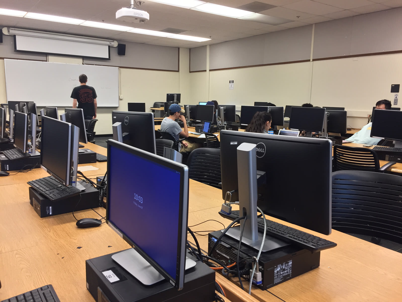 A computer lab with rows of desktop monitors and office chairs.