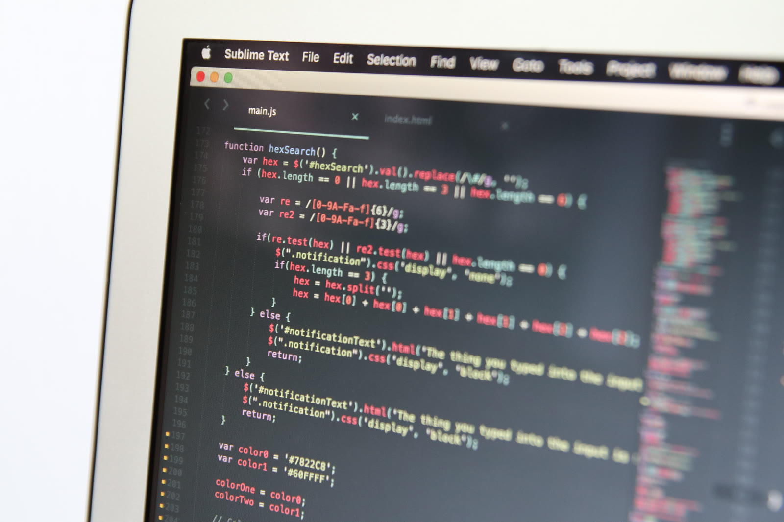 A close-up of a laptop screen filled with colorful lines of code in a text editor.