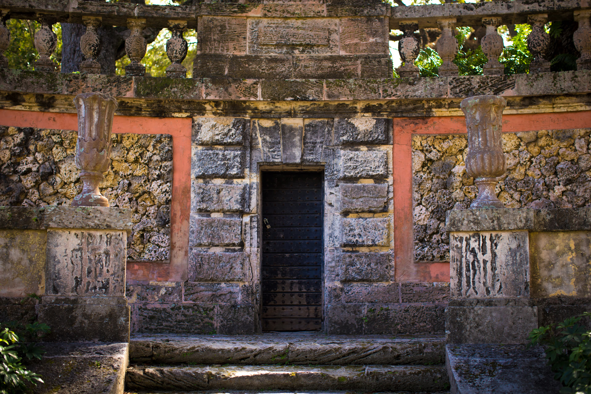 A weathered wooden door with a metal padlock, set in a rough stone wall.