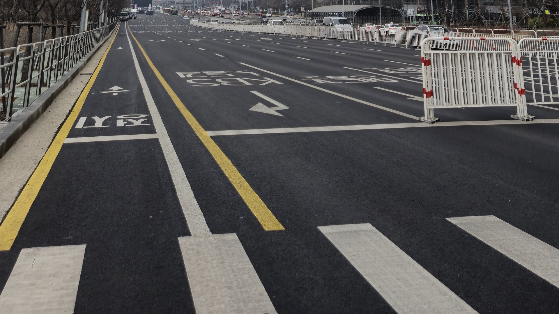 A wide intersection on Yeouido-daero in Seoul, with crosswalks, cars, and glass office towers under a bright sky.