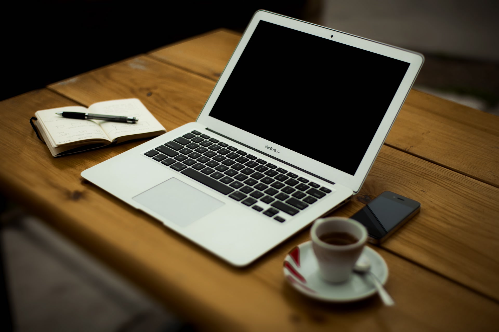 A wooden home-office desk with an open laptop, an external monitor, a keyboard, and a mouse.