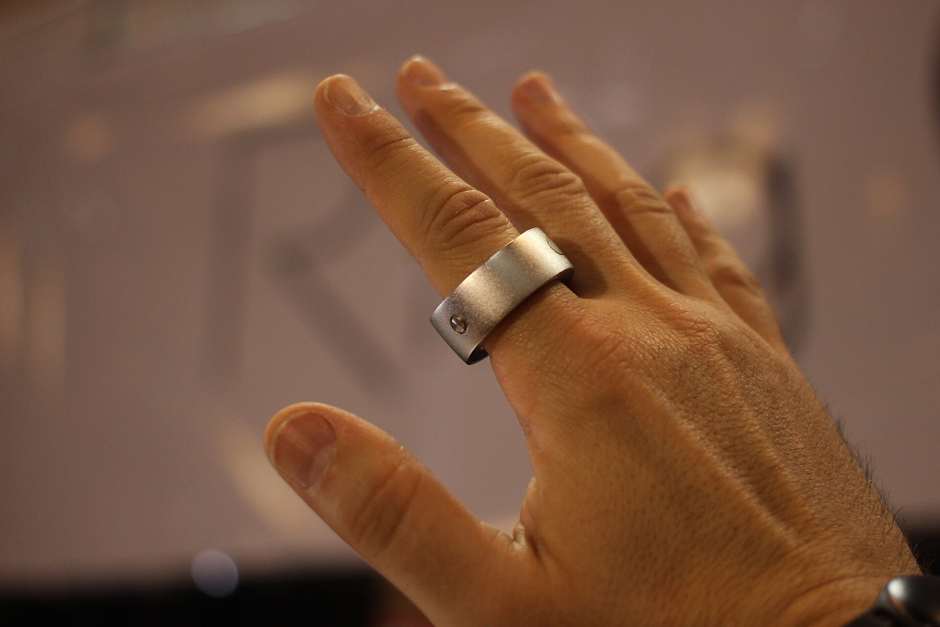 A close-up of a hand wearing a black smart ring on the index finger.