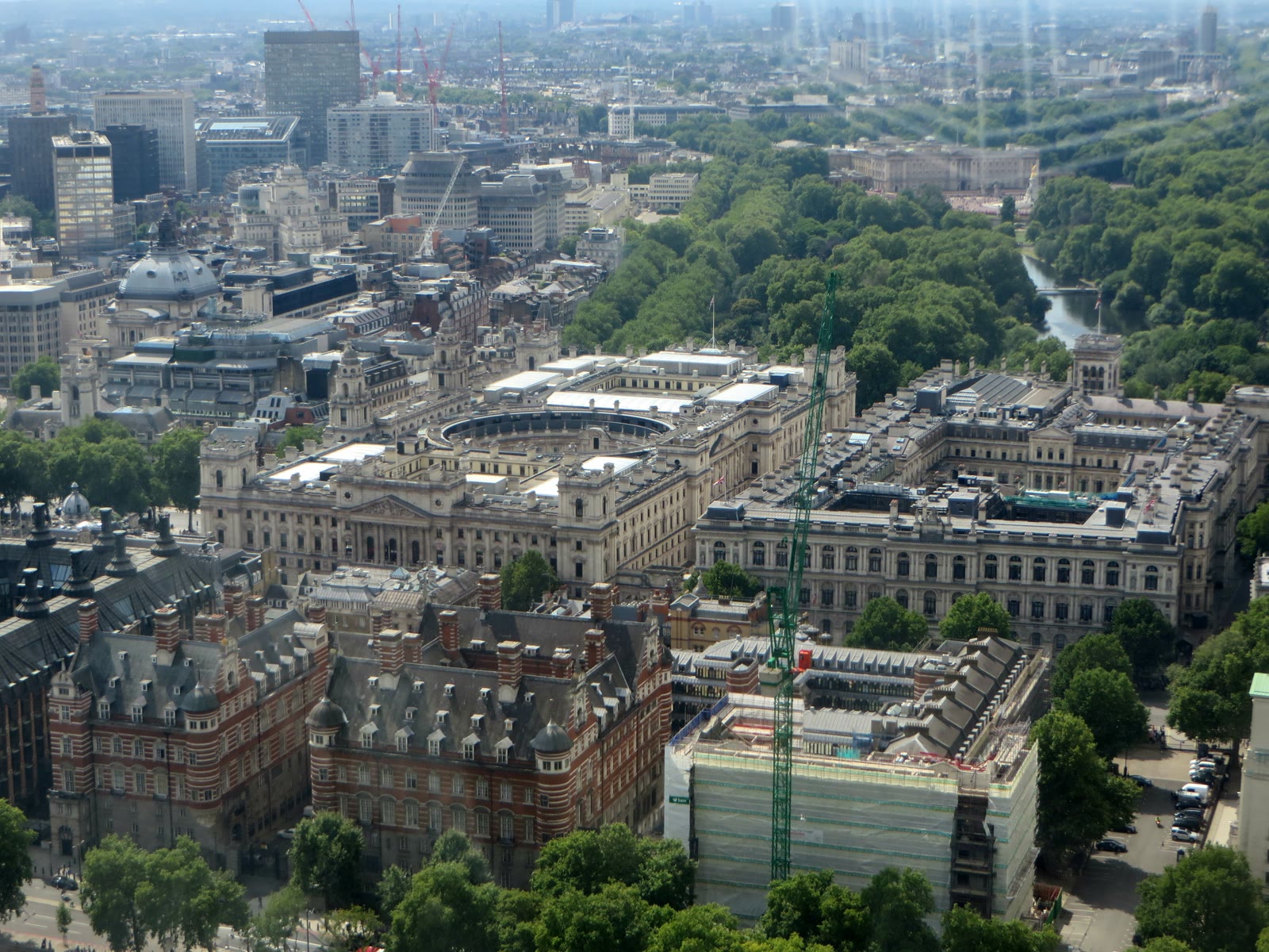 Whitehall in London seen from above, with government buildings along the street, a red double-decker bus, and the Thames in the foreground.