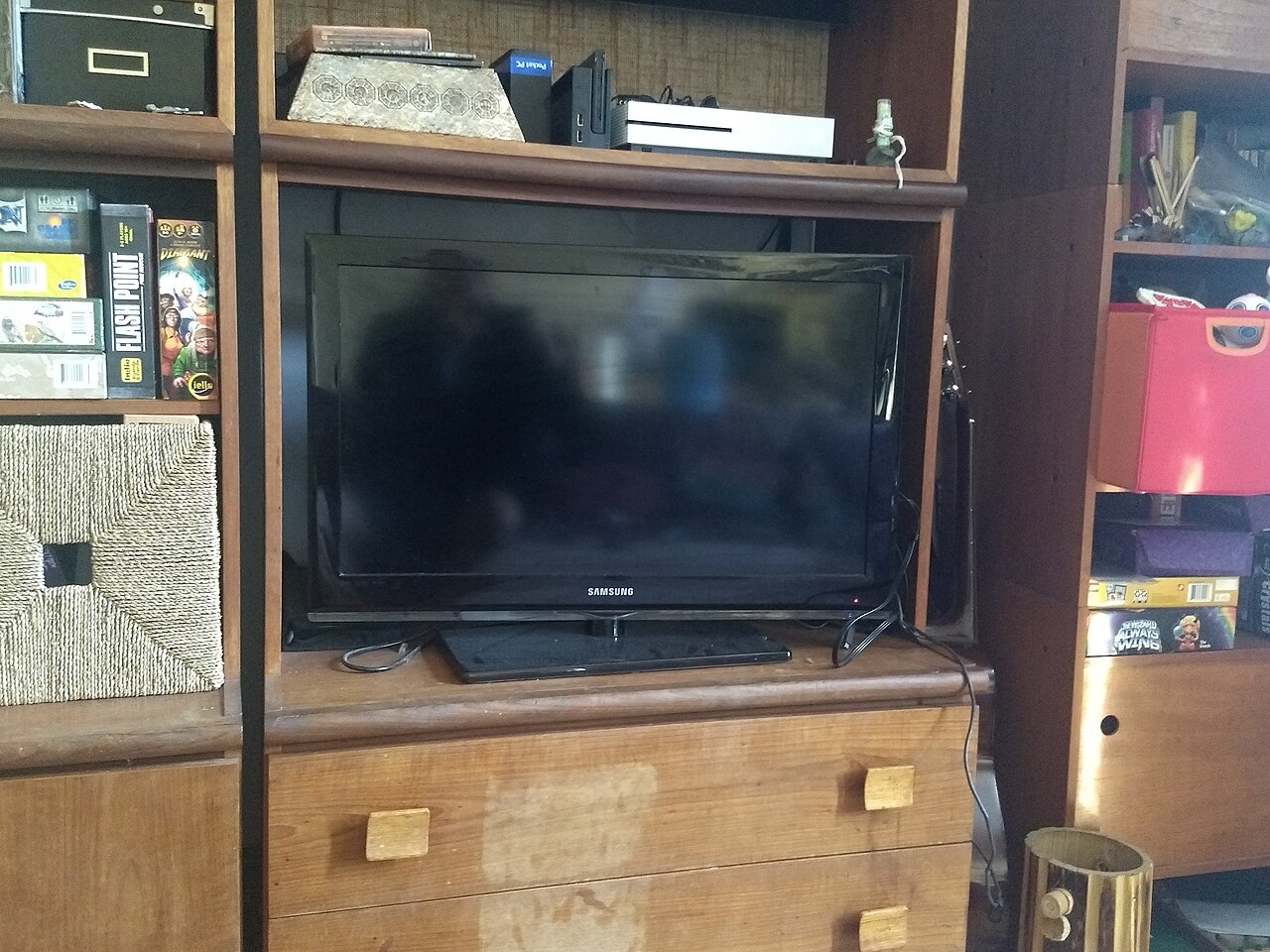 A flat-screen television on a bookshelf in a living room, with the screen off.