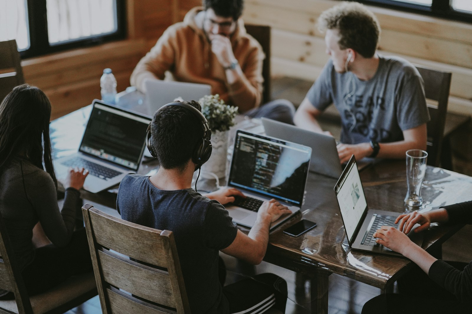 Team of colleagues collaborating around a table with laptops in a bright office