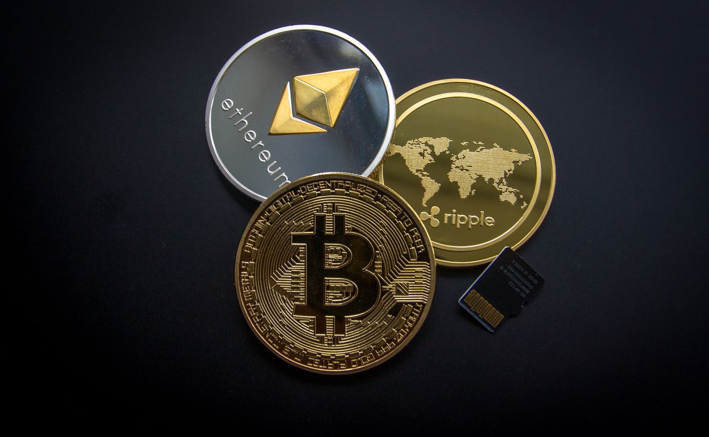 Gold Bitcoin coins stacked in front of a blurred trading chart