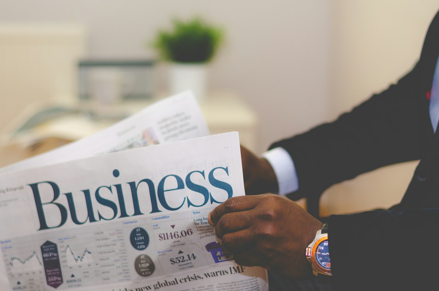 Person in a suit holding a Business newspaper section with currency charts