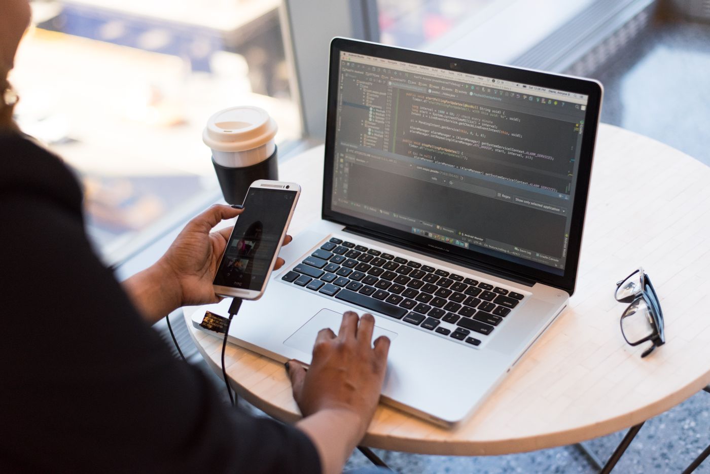 Person coding on a laptop at a wooden desk