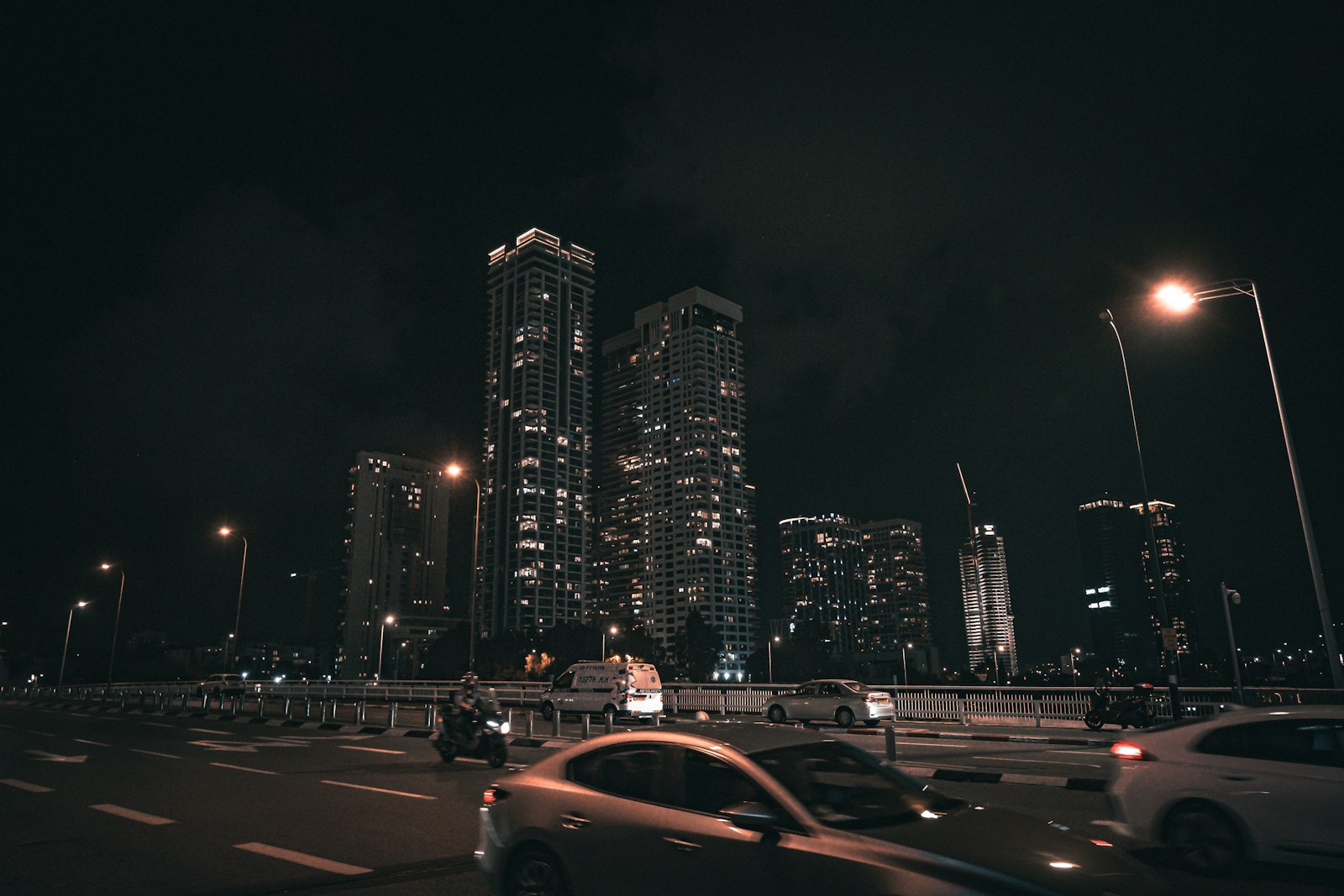 Night city traffic and lit skyscrapers with motion-blurred cars