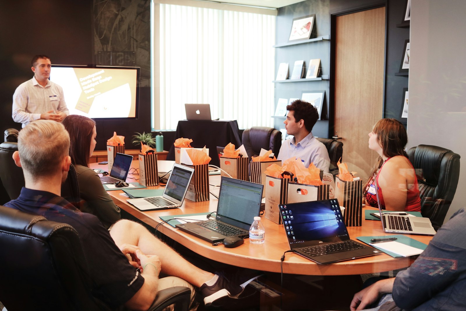 Team collaborating around a conference table with laptops in a bright office