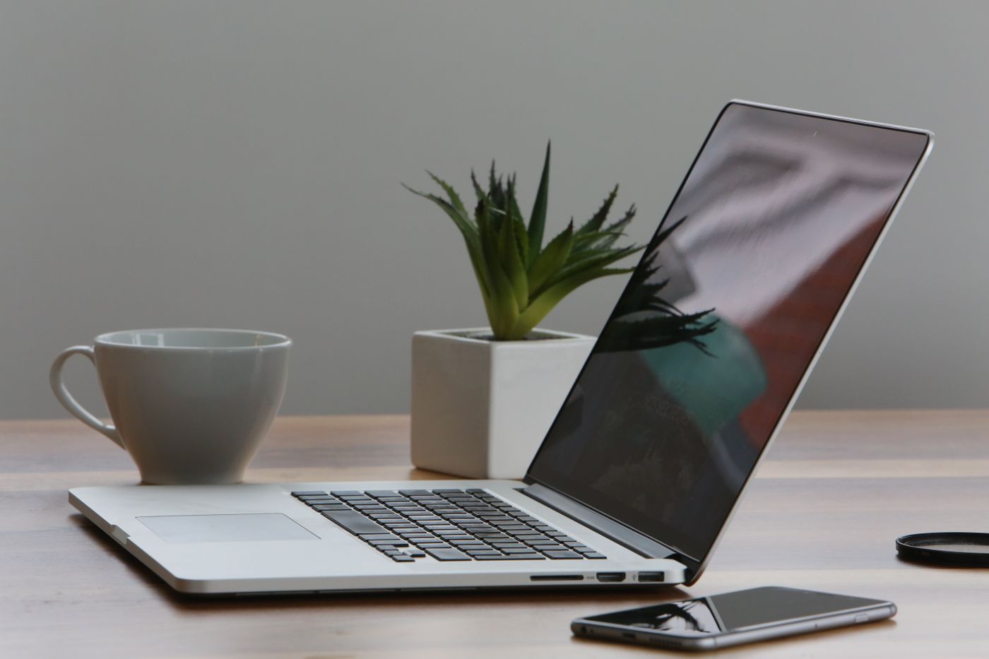 Laptop open on a desk with papers and a coffee cup nearby
