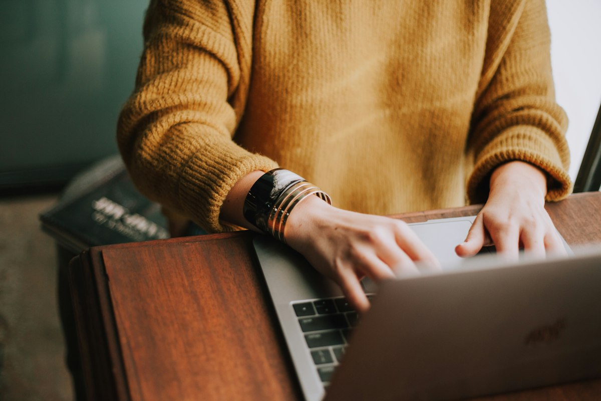 Person working on a laptop with coffee on a wooden table