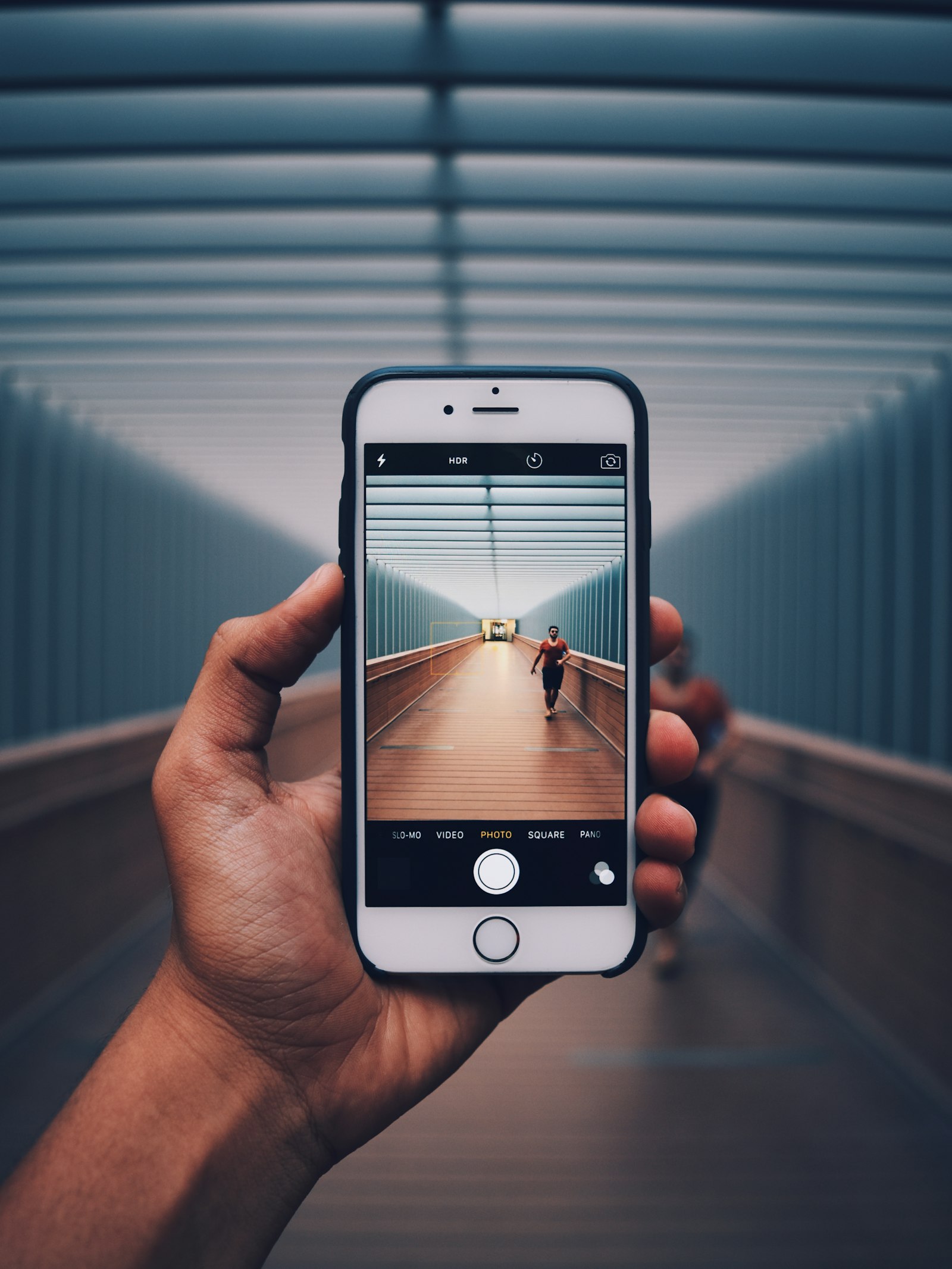Hand holding a smartphone with the camera app open in a covered walkway