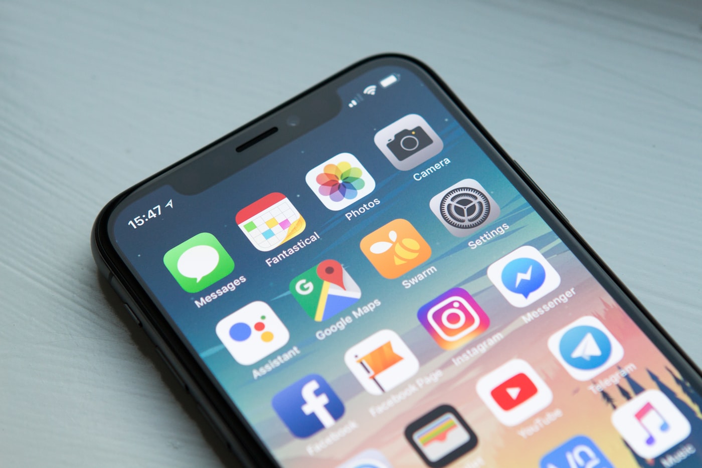 iPhone home screen with app icons on a light wooden surface