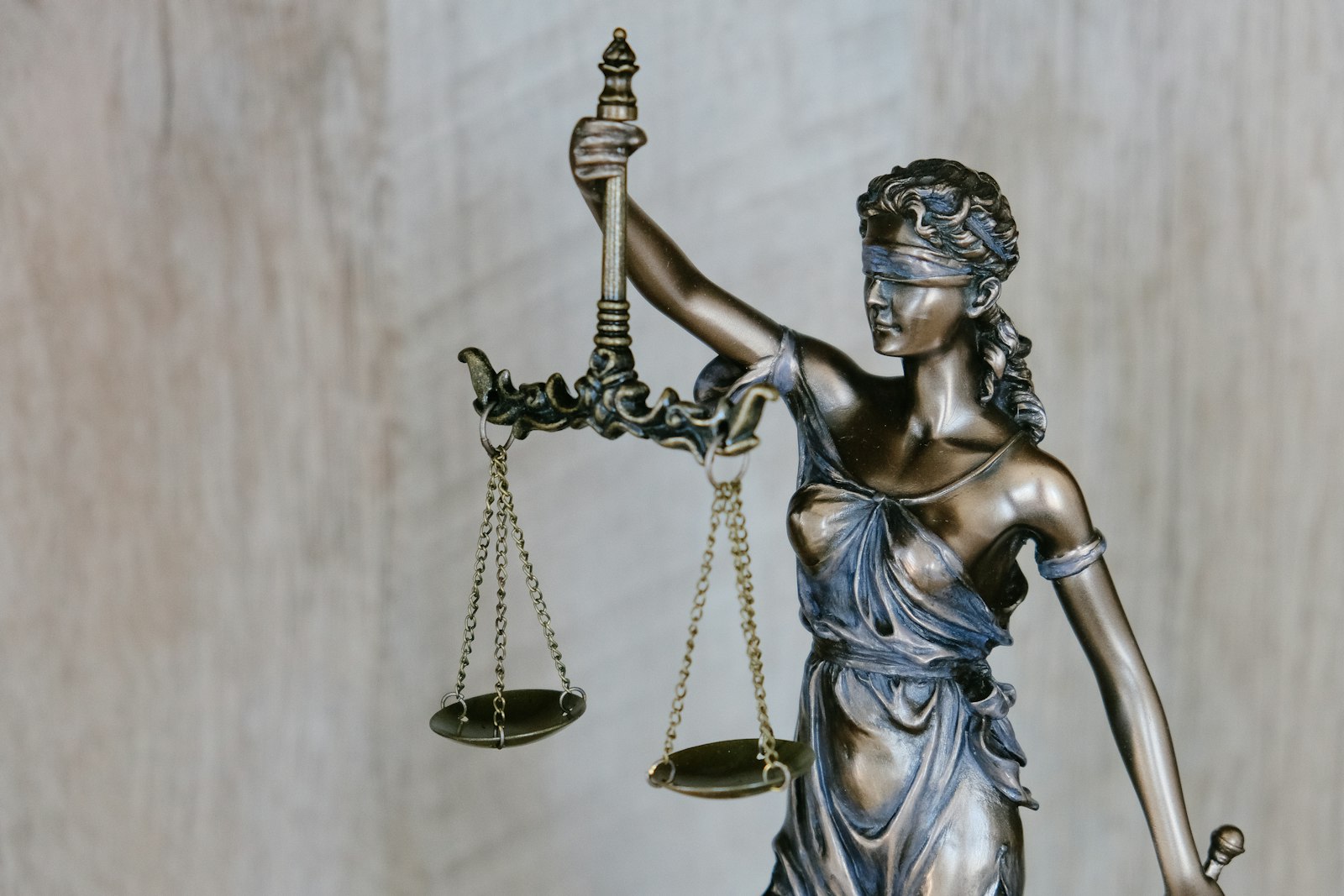 Bronze Lady Justice statue holding scales against a blurred background