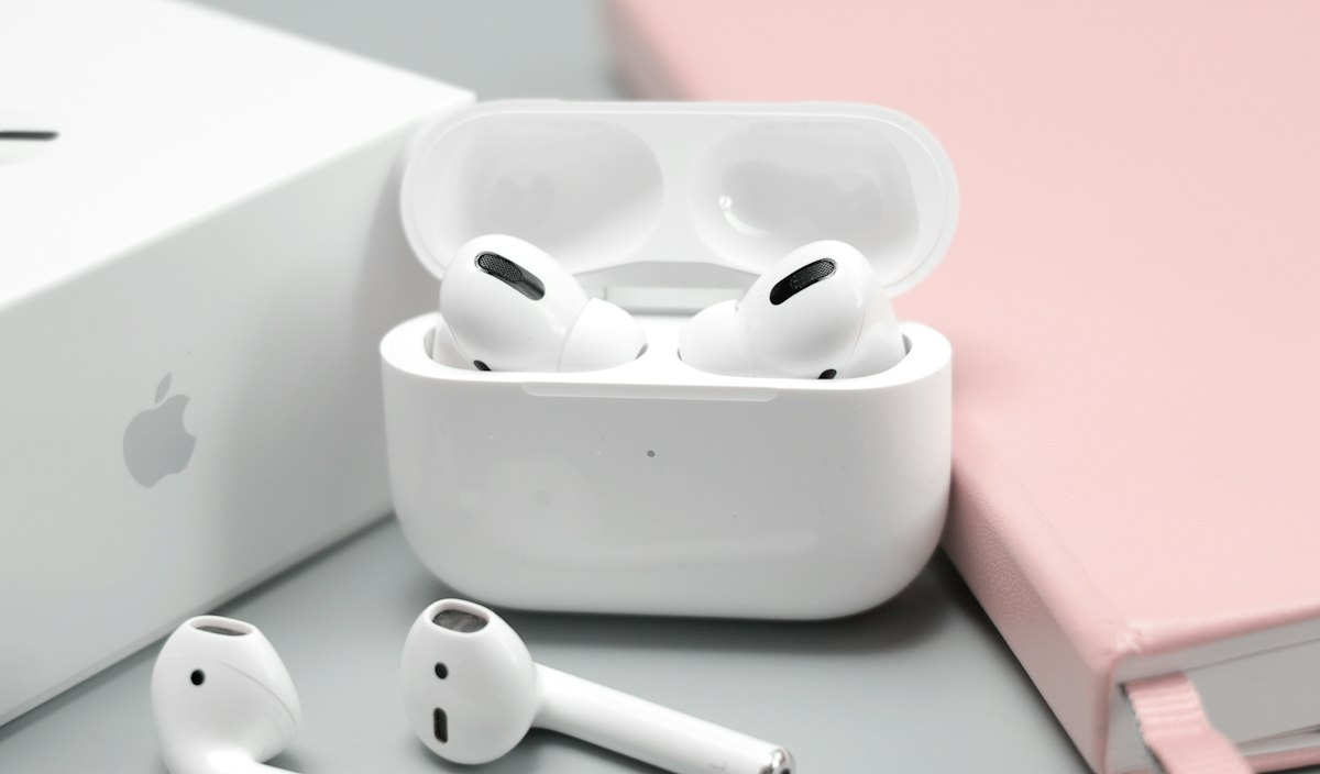 White wireless earbuds in an open charging case on a gray desk
