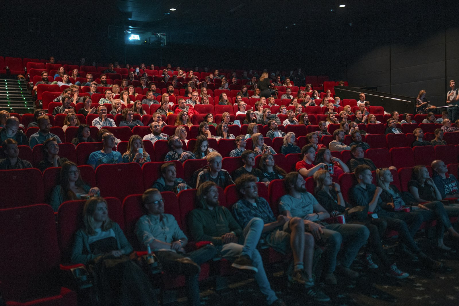 Audience seated in a dim movie theater facing the screen