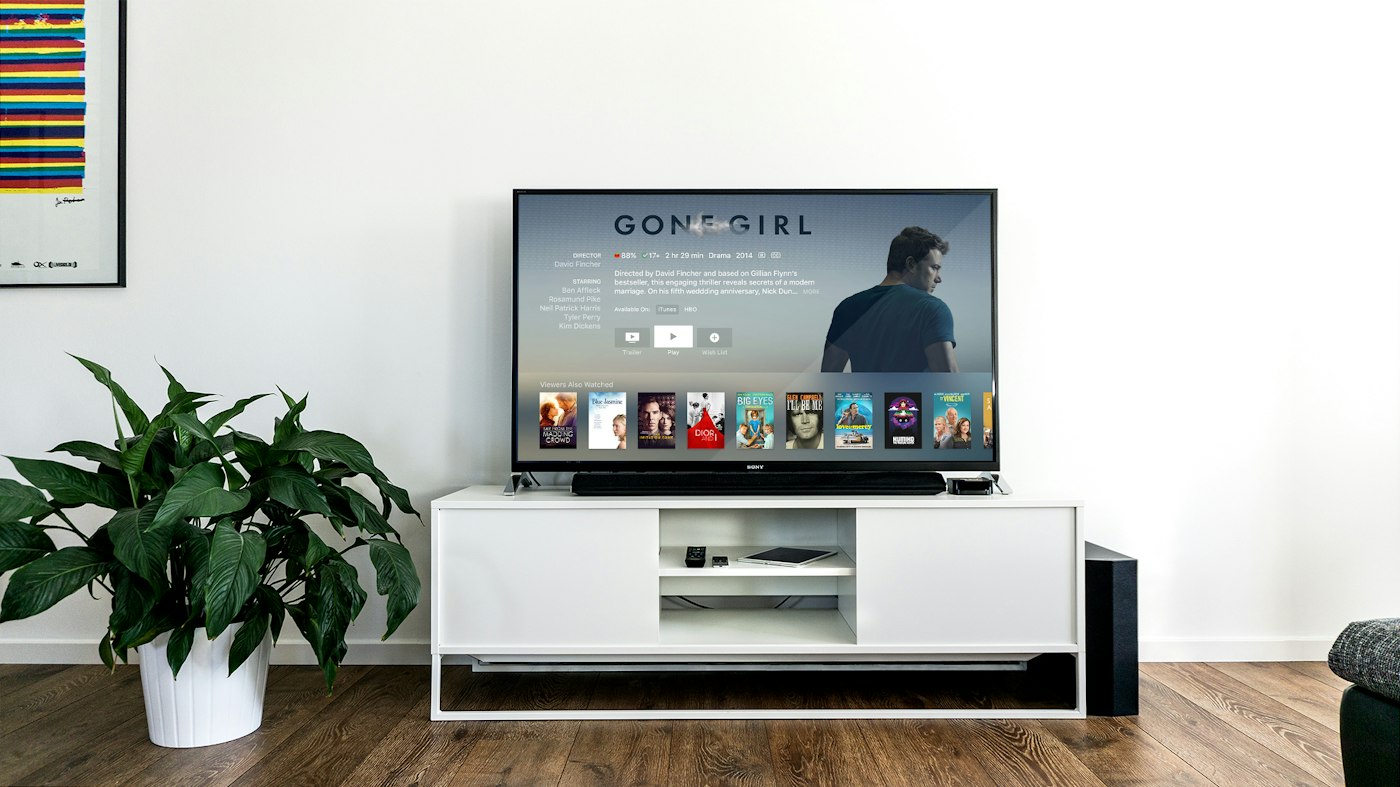 Living room TV on a white console showing a streaming movie detail page