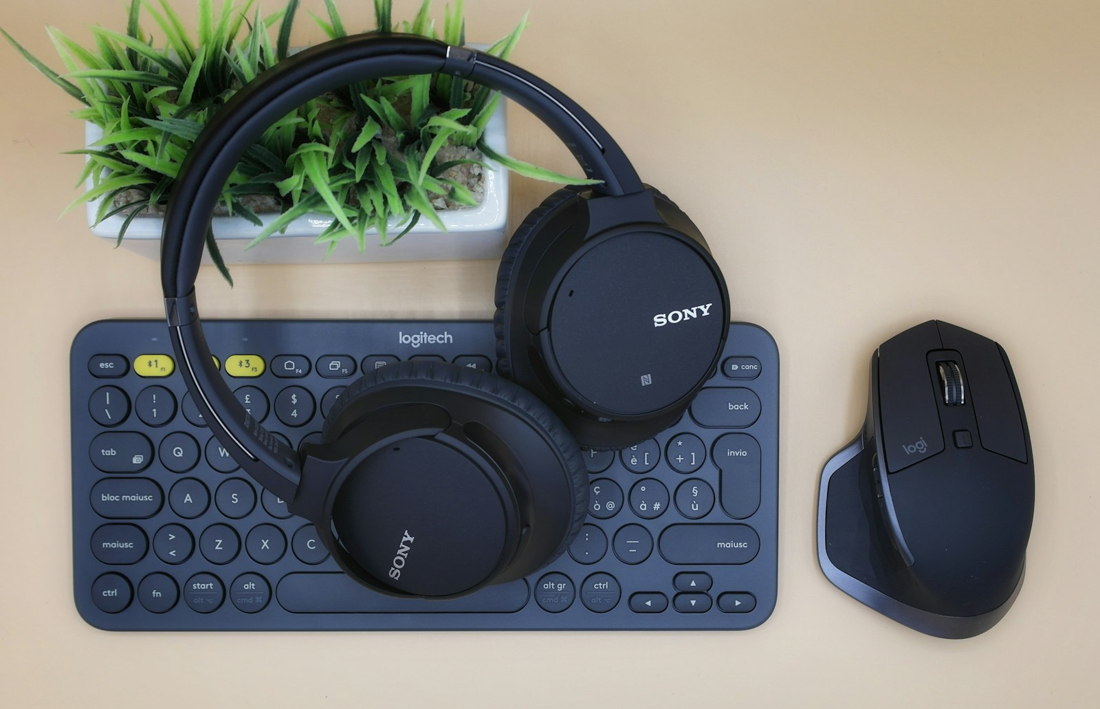 Logitech MX Master mouse and compact keyboard with headphones on a desk