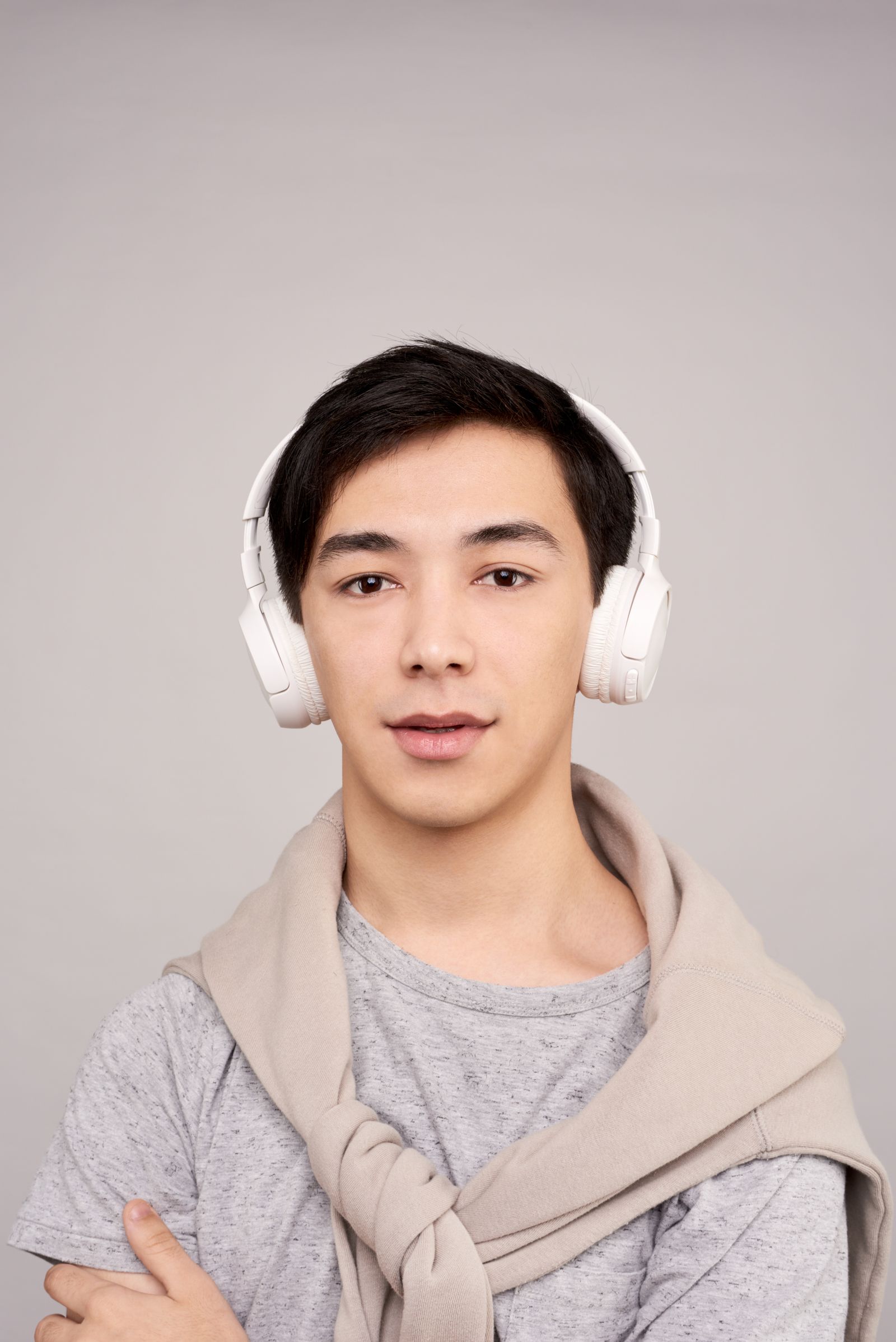 Person wearing white over-ear headphones with arms crossed