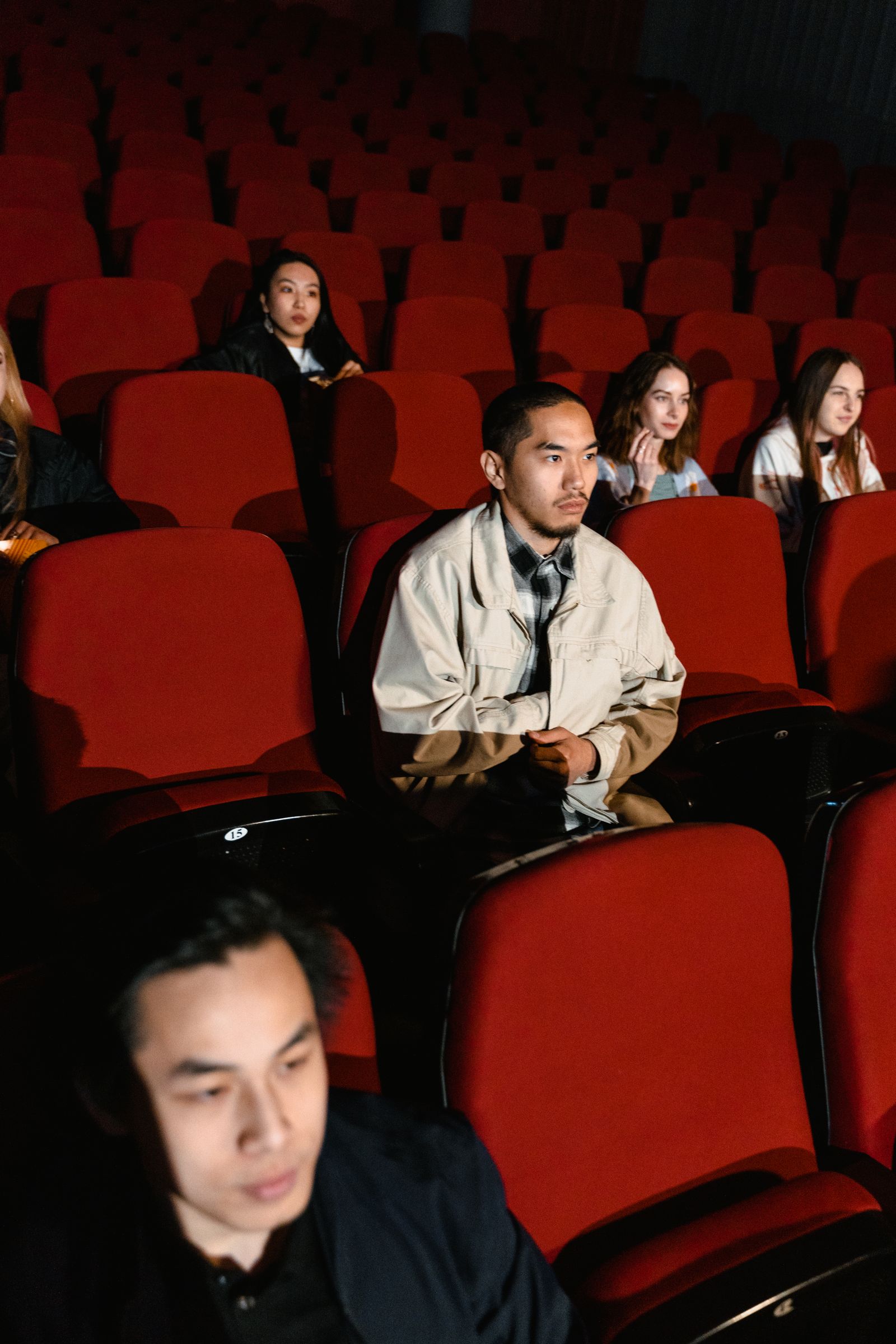 People sitting in red cinema seats watching a movie