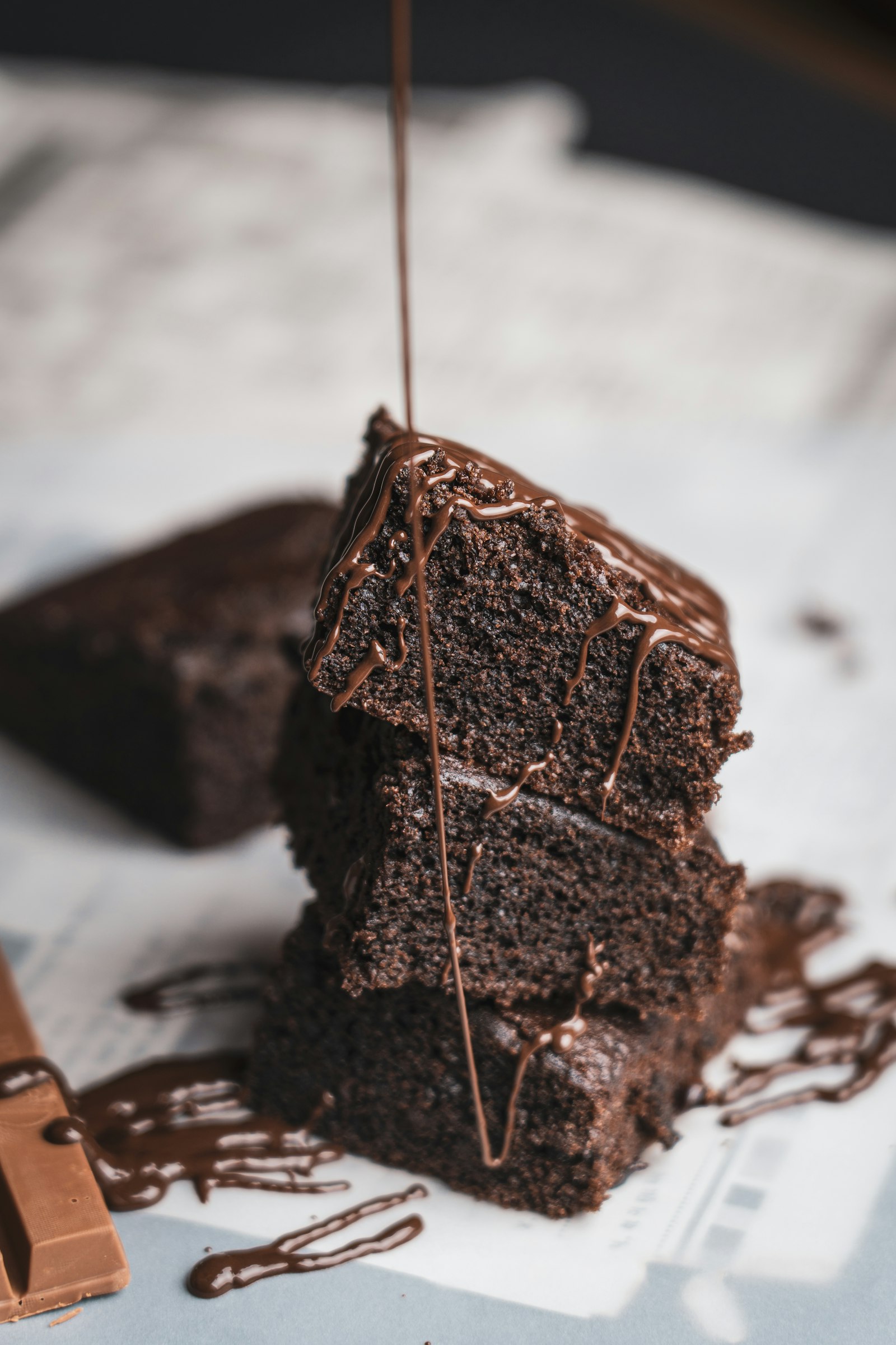 Stack of dark chocolate brownies with liquid chocolate poured over the top