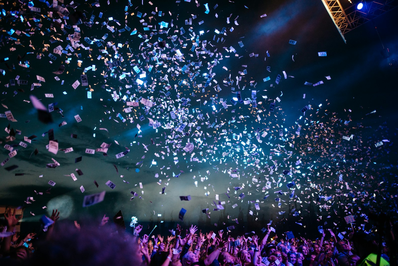 Crowd at a night event with blue lights and confetti falling