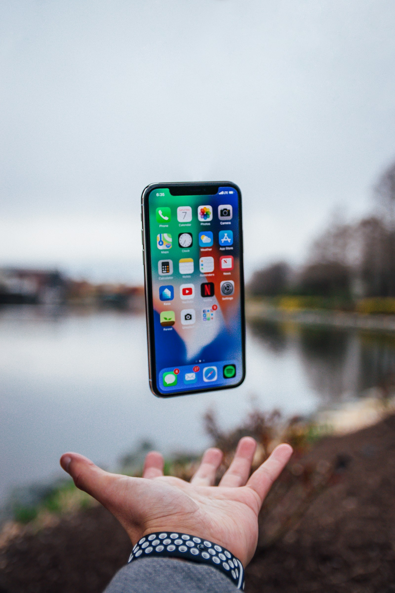 Smartphone floating above an open hand outdoors