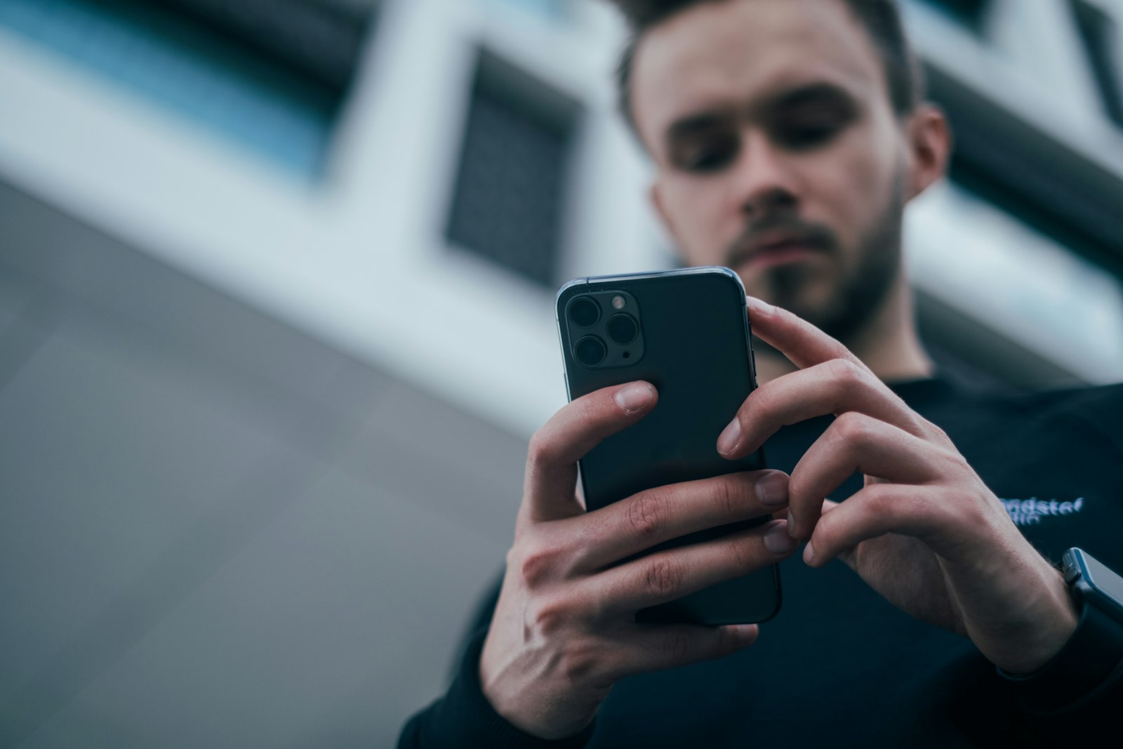 Person holding a smartphone in front of a city building