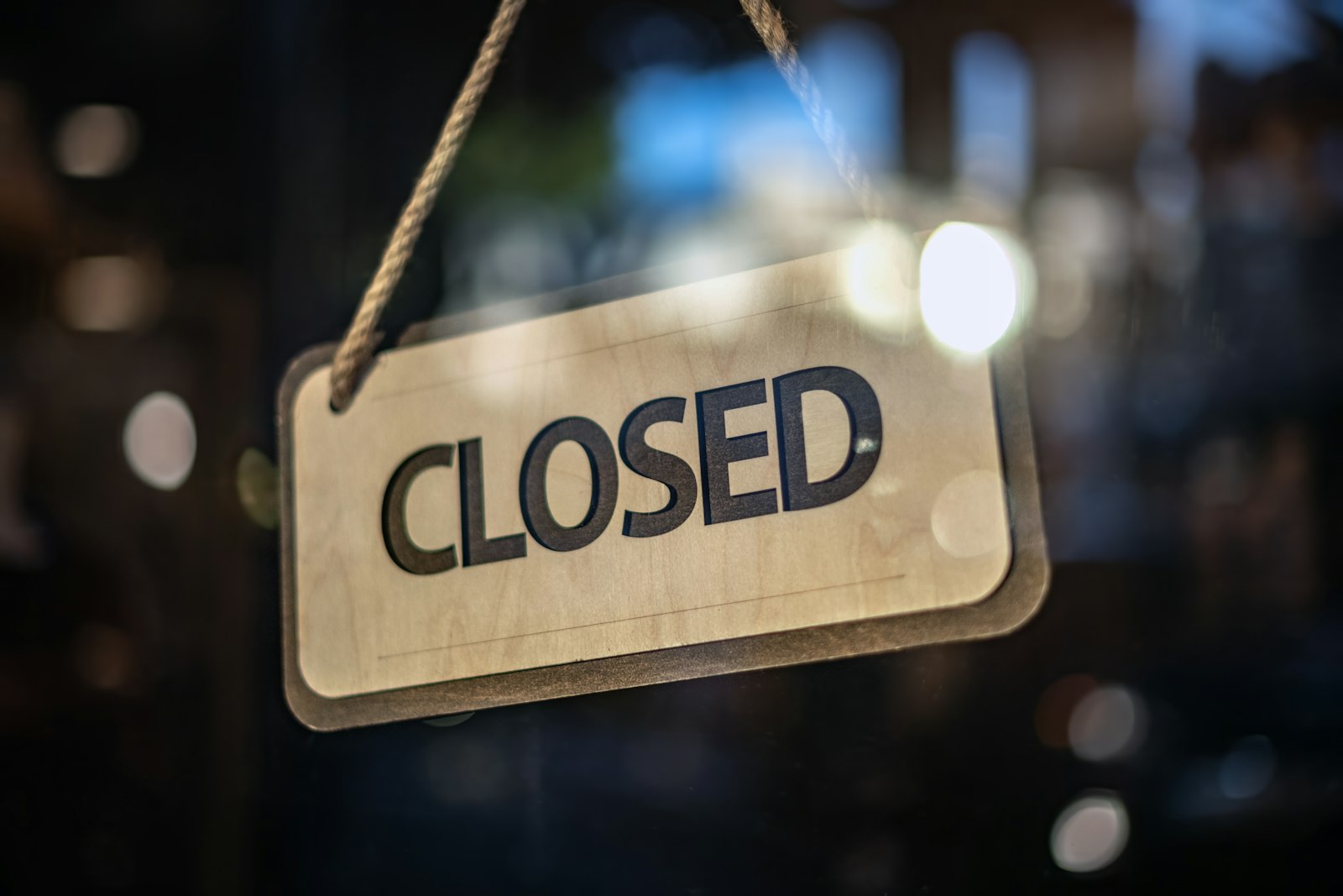 Wooden closed sign hanging in a shop window at night