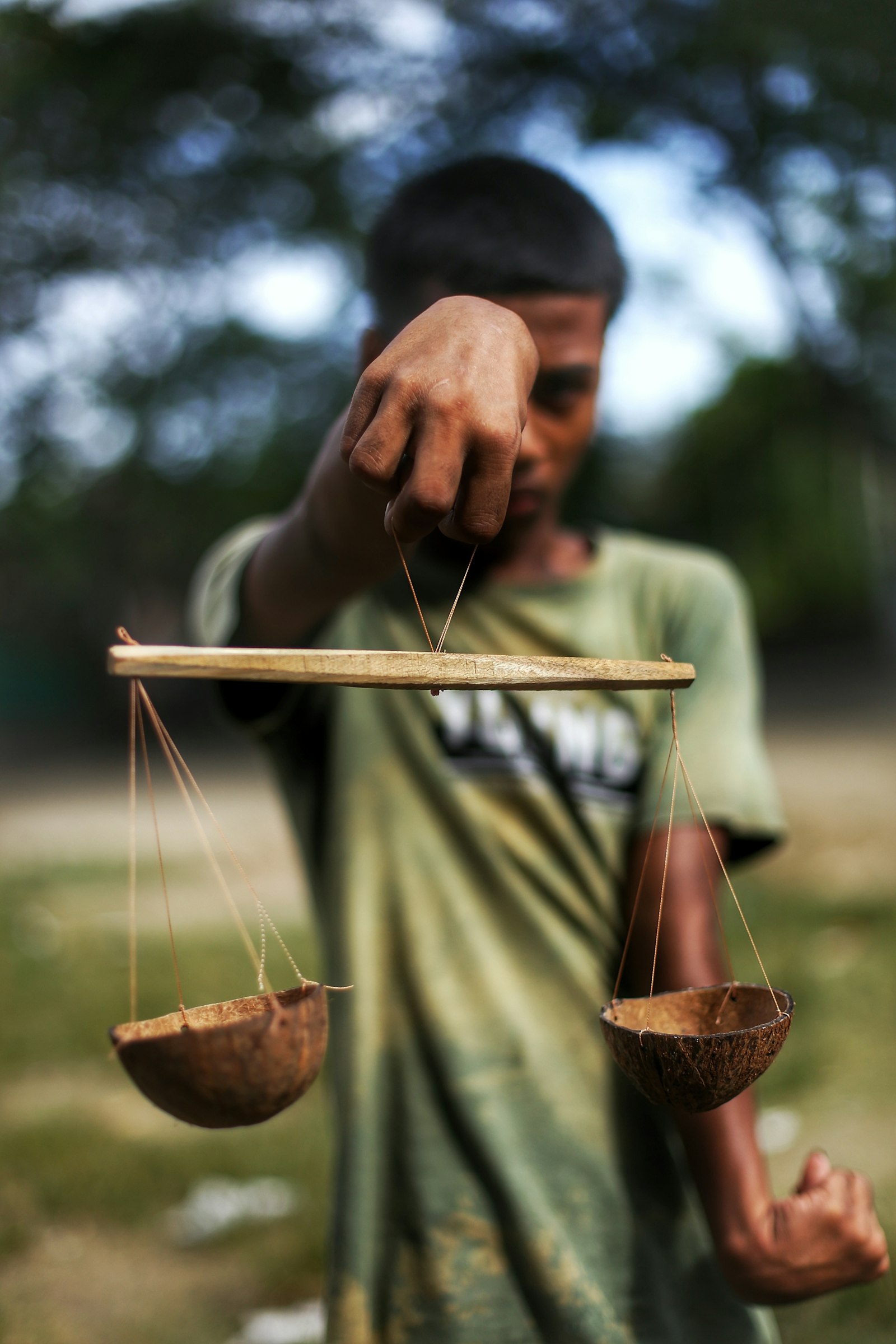 Person holding a wooden balance scale outdoors in soft light