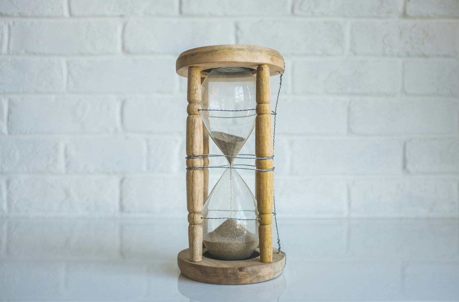 Clear glass hourglass in a brown wooden frame with sand running through it
