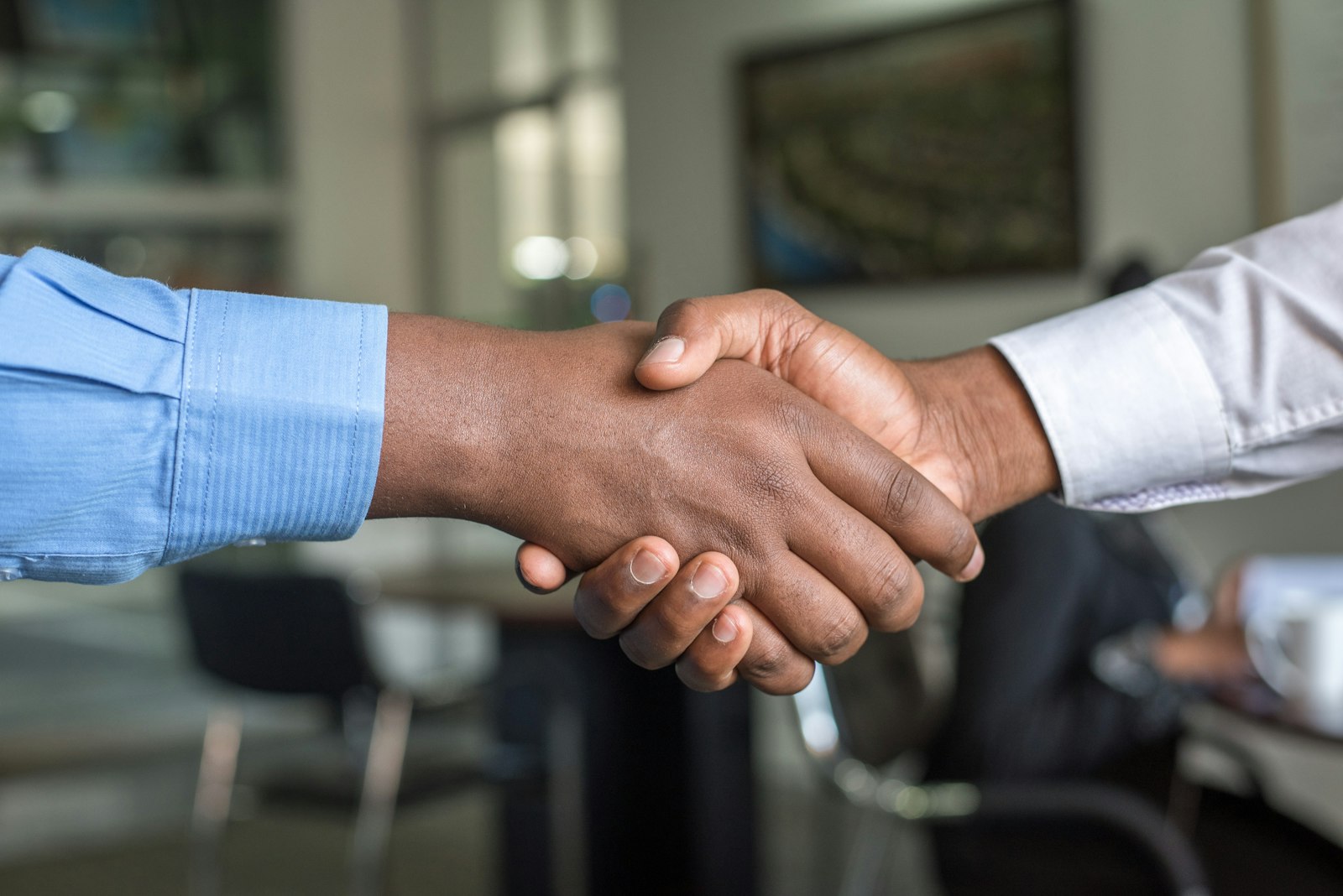 Close-up handshake between two people in a bright office