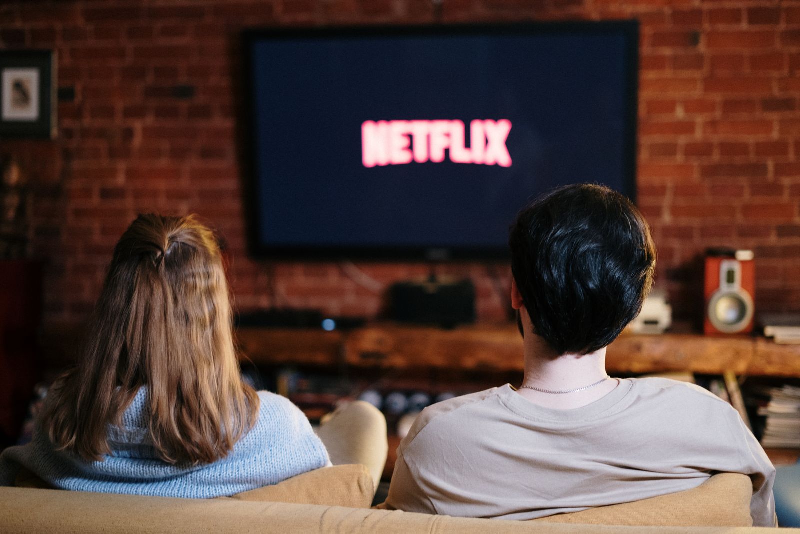 Couple on a couch facing a television with a streaming logo on screen