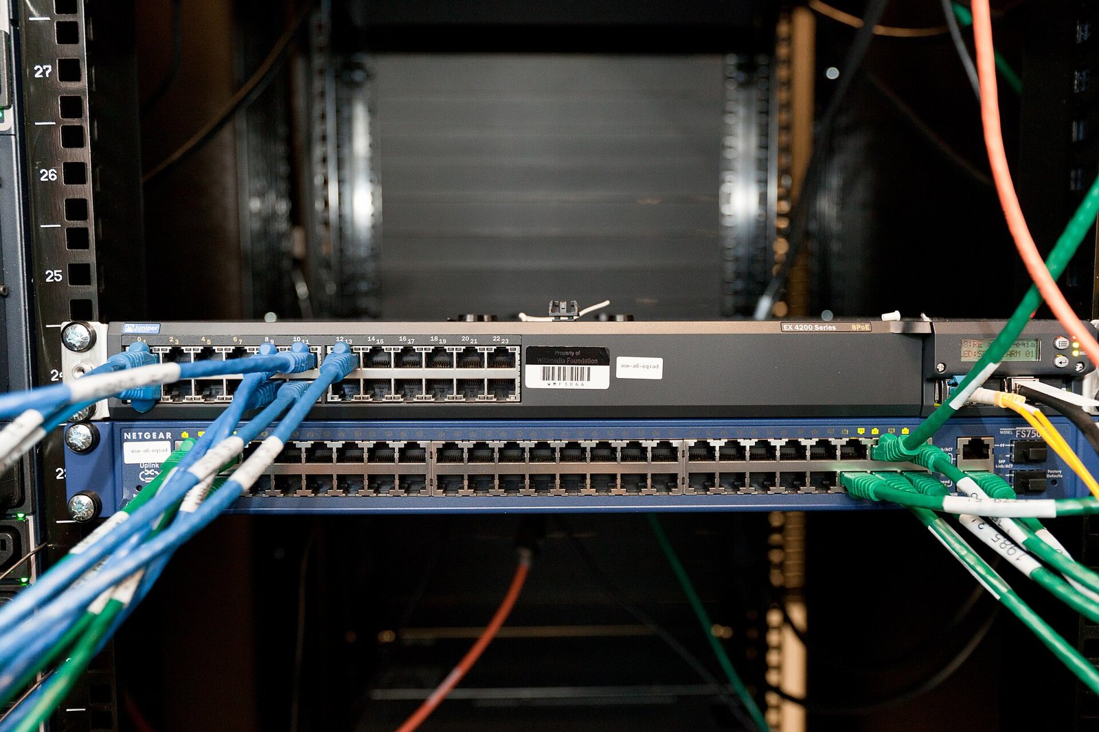 A rack-mounted network switch with blue and green cables plugged into its ports