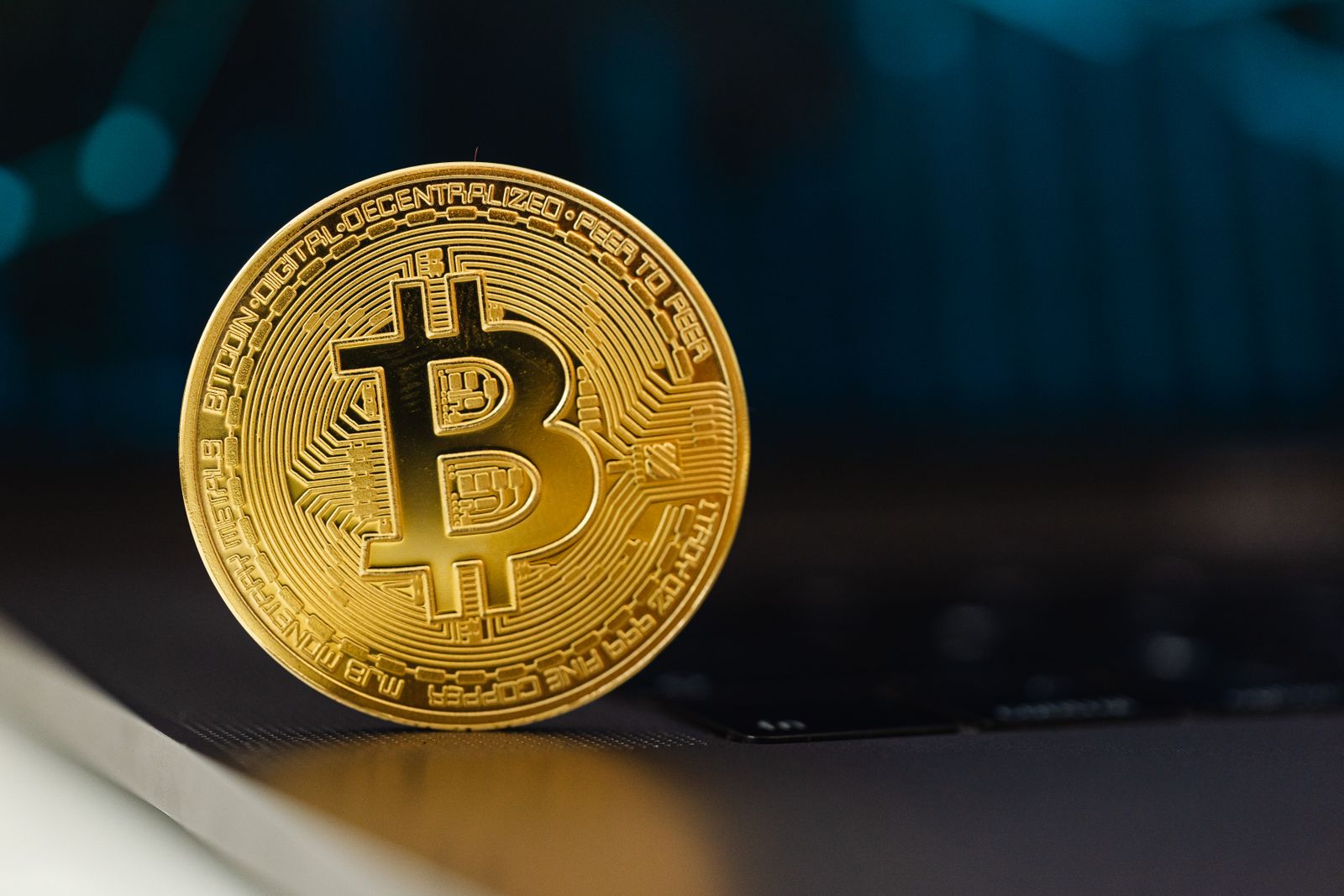 Gold Bitcoin token resting on a laptop keyboard