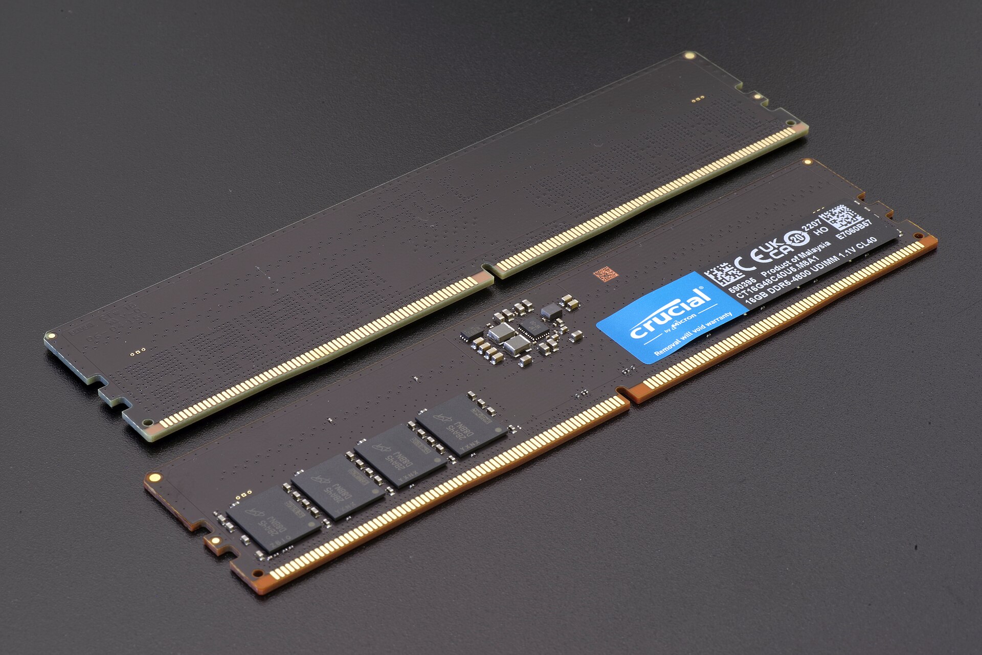 Two DDR5 memory modules lying on a dark surface, one showing its memory chips