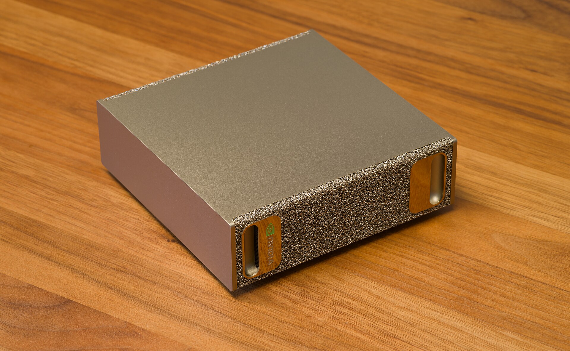 Nvidia DGX Spark mini computer with a gold metal-foam front on a wooden desk