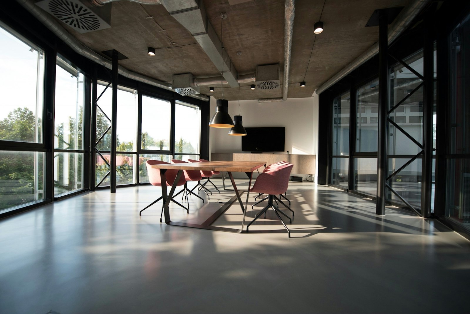 Empty modern conference room with a long wood table and pink chairs