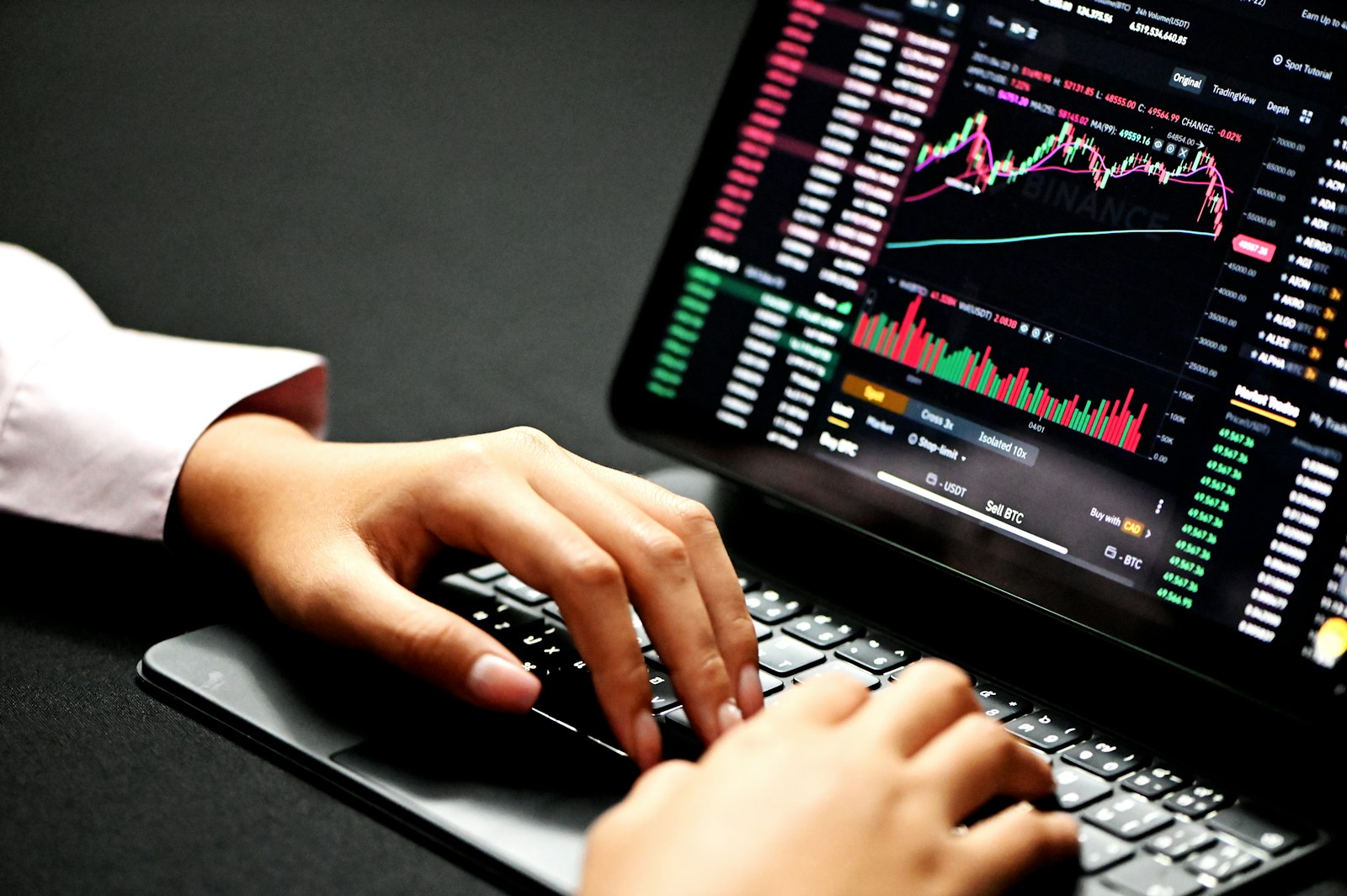 Hands typing on a laptop showing a crypto trading chart