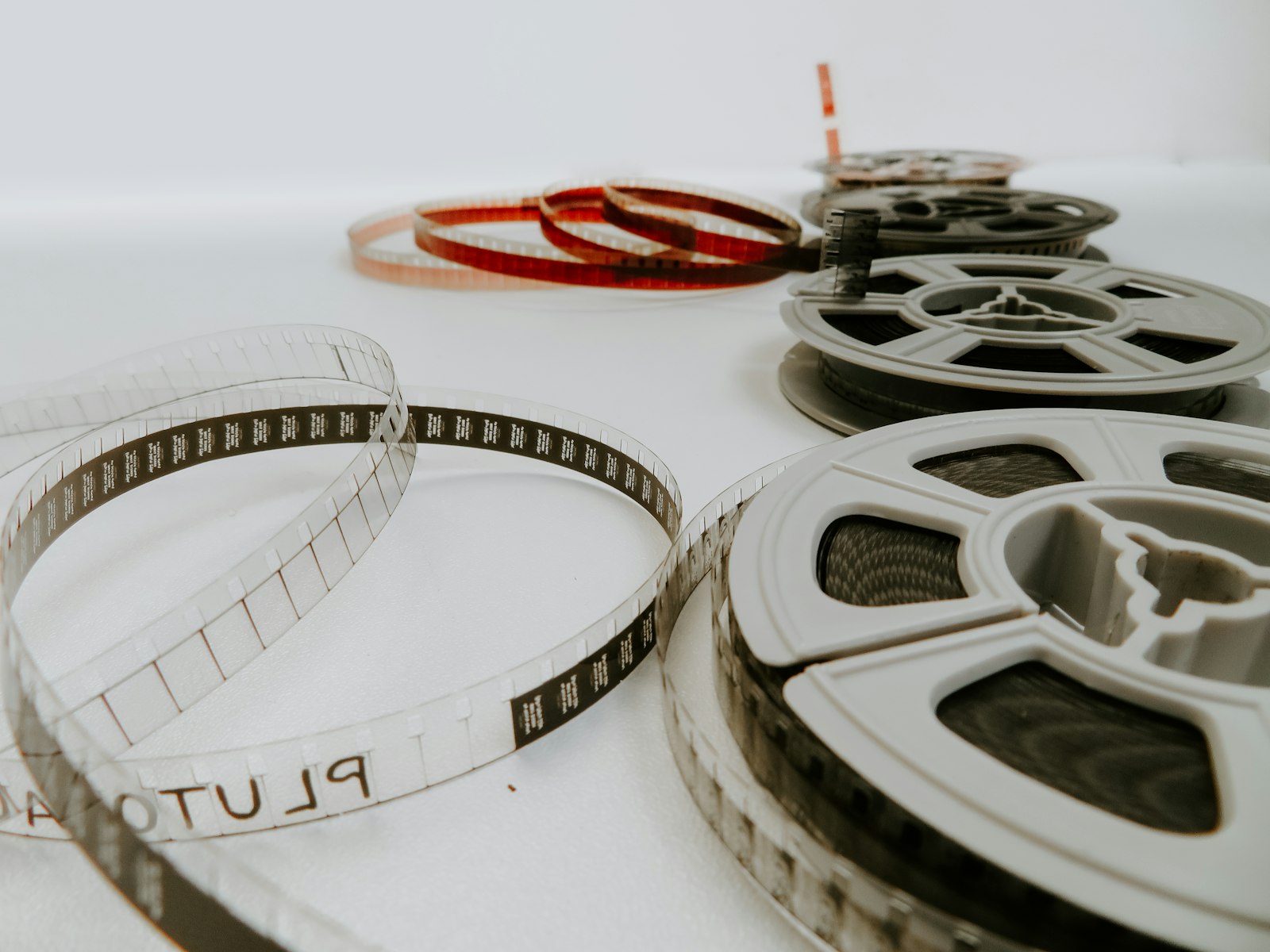 Vintage film reels and loose film strips on a light surface